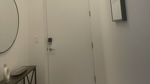 En hvid dør med en moderne lampe over og et spejl på væggen til højre.