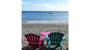 Two beach chairs facing the ocean with a table between them.