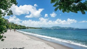 A beach with a clear sky, calm sea, and distant mountains. - Elegance - Sea view, private beach access, swimming pool (Schoelcher)
