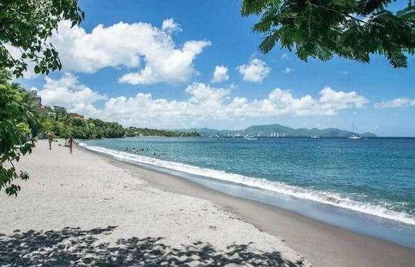A beach with a clear sky, calm sea, and distant mountains. - Elegance - Sea view, private beach access, swimming pool (Schoelcher)