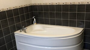 Un bagno moderno con una vasca freestanding, pareti rivestite di piastrelle bianche e nere e pavimento grigio.