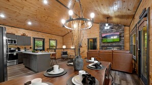 A modern kitchen with a central island, grey cabinets, and a dining area with a wooden table set for four. - Private Location Hot tub, Pool table, Multicade, Free Attraction Passes (Sevierville)