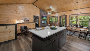 A wooden cabin interior with a central island, dining area, and a fireplace. - Private Location Hot tub, Pool table, Multicade, Free Attraction Passes (Sevierville)