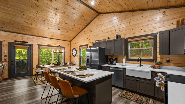 A spacious kitchen with wooden ceiling, a central island, bar stools, and a view of the outdoors. - Private Location Hot tub, Pool table, Multicade, Free Attraction Passes (Sevierville)