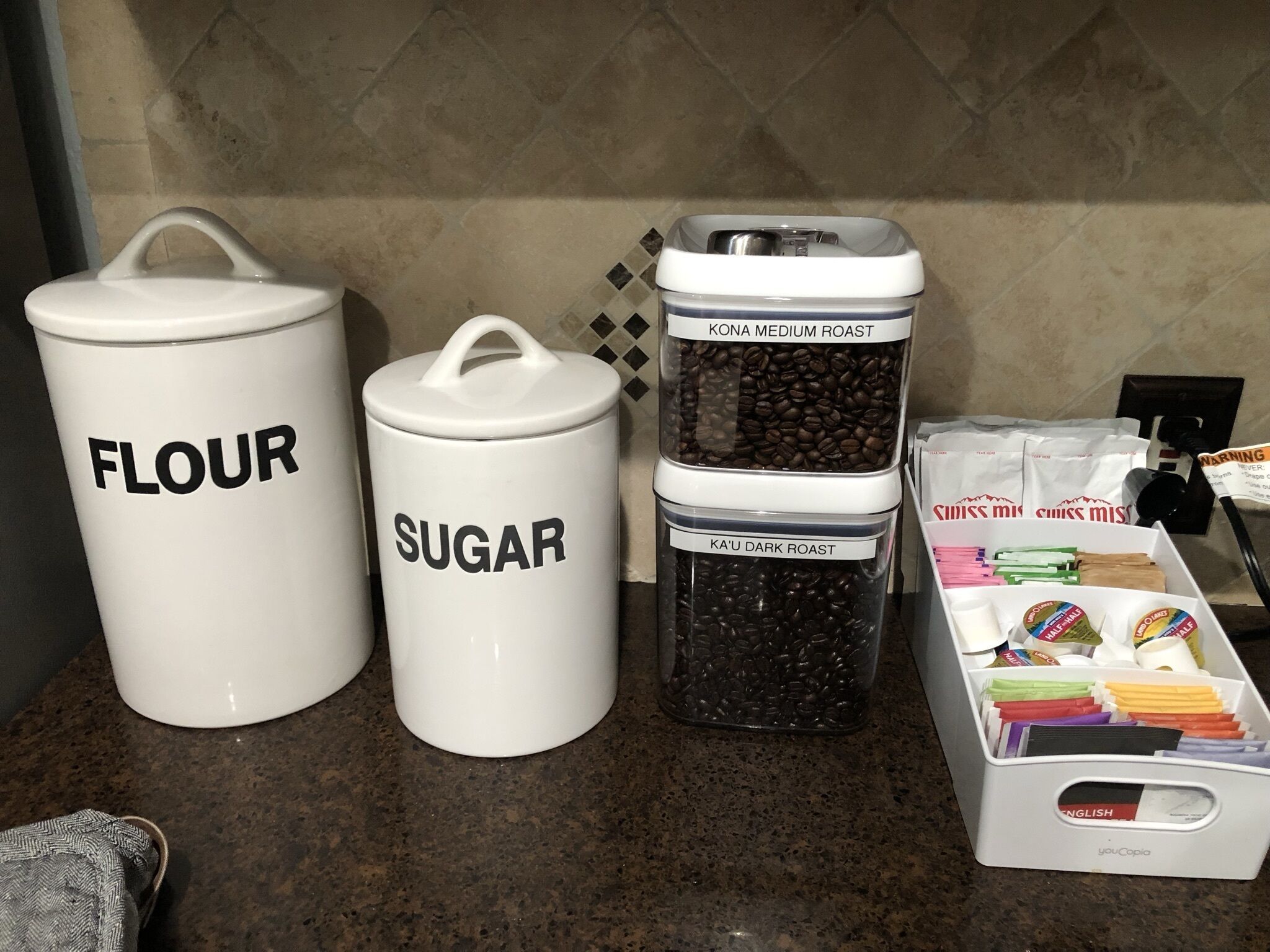 Kitchen storage containers labeled 'FLOUR' and 'SUGAR' on a countertop.