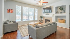 A living room with hardwood floors, a gray sofa, a coffee table, and a fireplace.