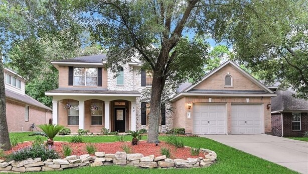 A two-story house with a stone facade, a front porch, and a garage.