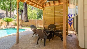 A covered patio area with a pool, outdoor furniture, and a ceiling fan.