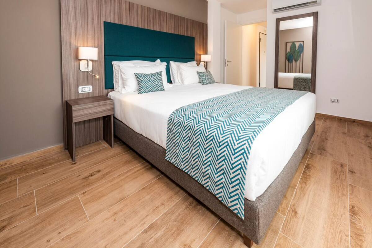 Een moderne hotelkamer met een groot bed, houten vloeren en een ingebouwde airconditioning.