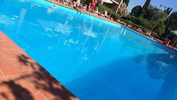 Una piscina al aire libre de temporada, sillones reclinables de piscina