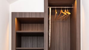 A walk-in closet with multiple shelves and hanging space, featuring a wooden finish and a bamboo hanger rod.