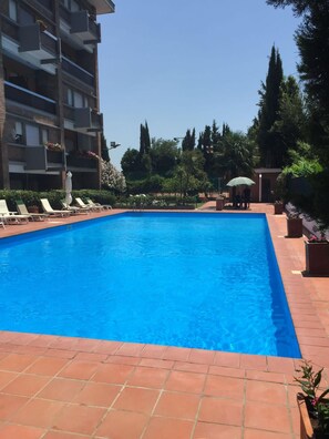 A rectangular swimming pool with a tiled edge, surrounded by lounge chairs and potted plants. - Aurelia Antica Suites & Apartments (Rome)