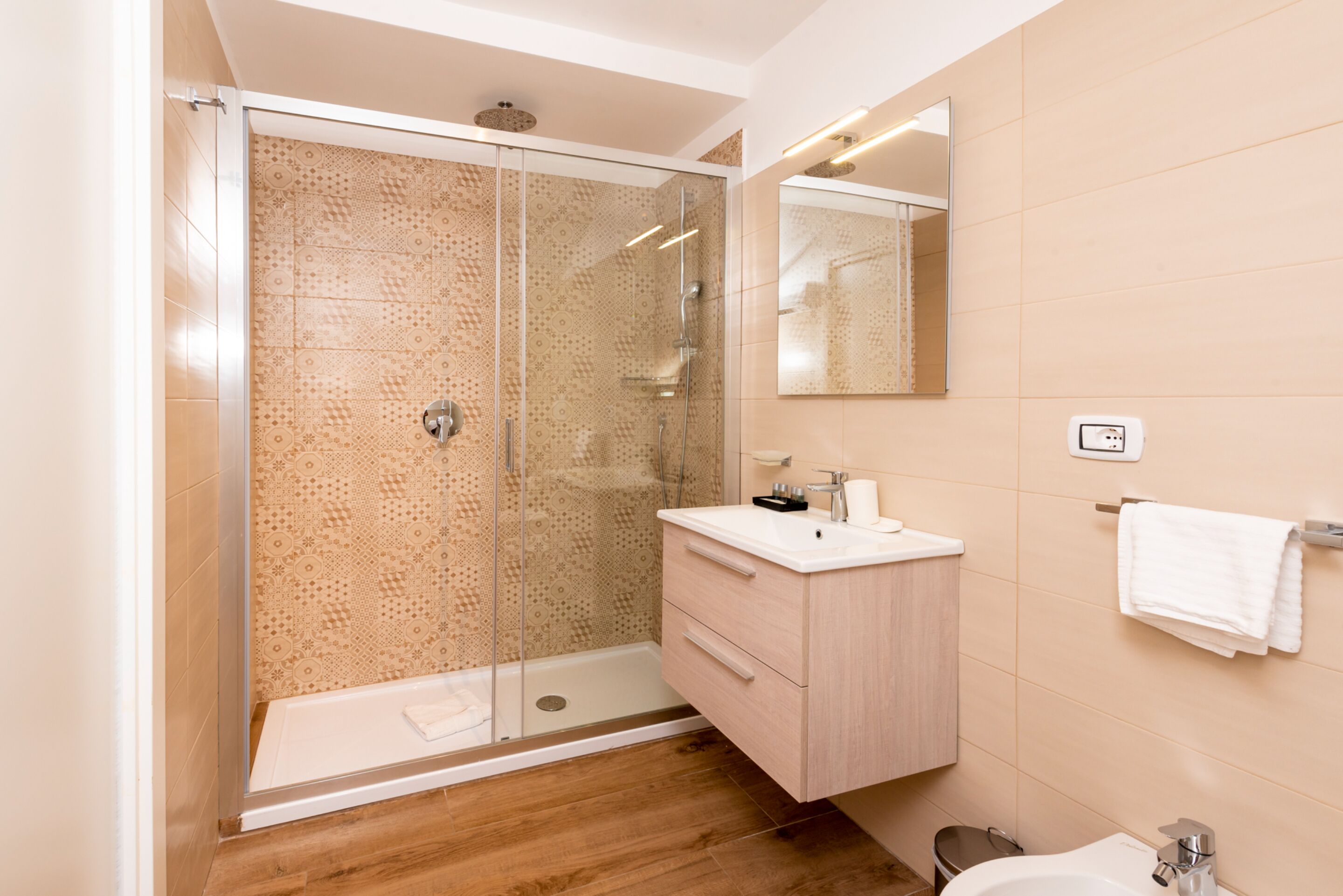 Un baño moderno con ducha de vidrio, tocador con espejo y retrete.