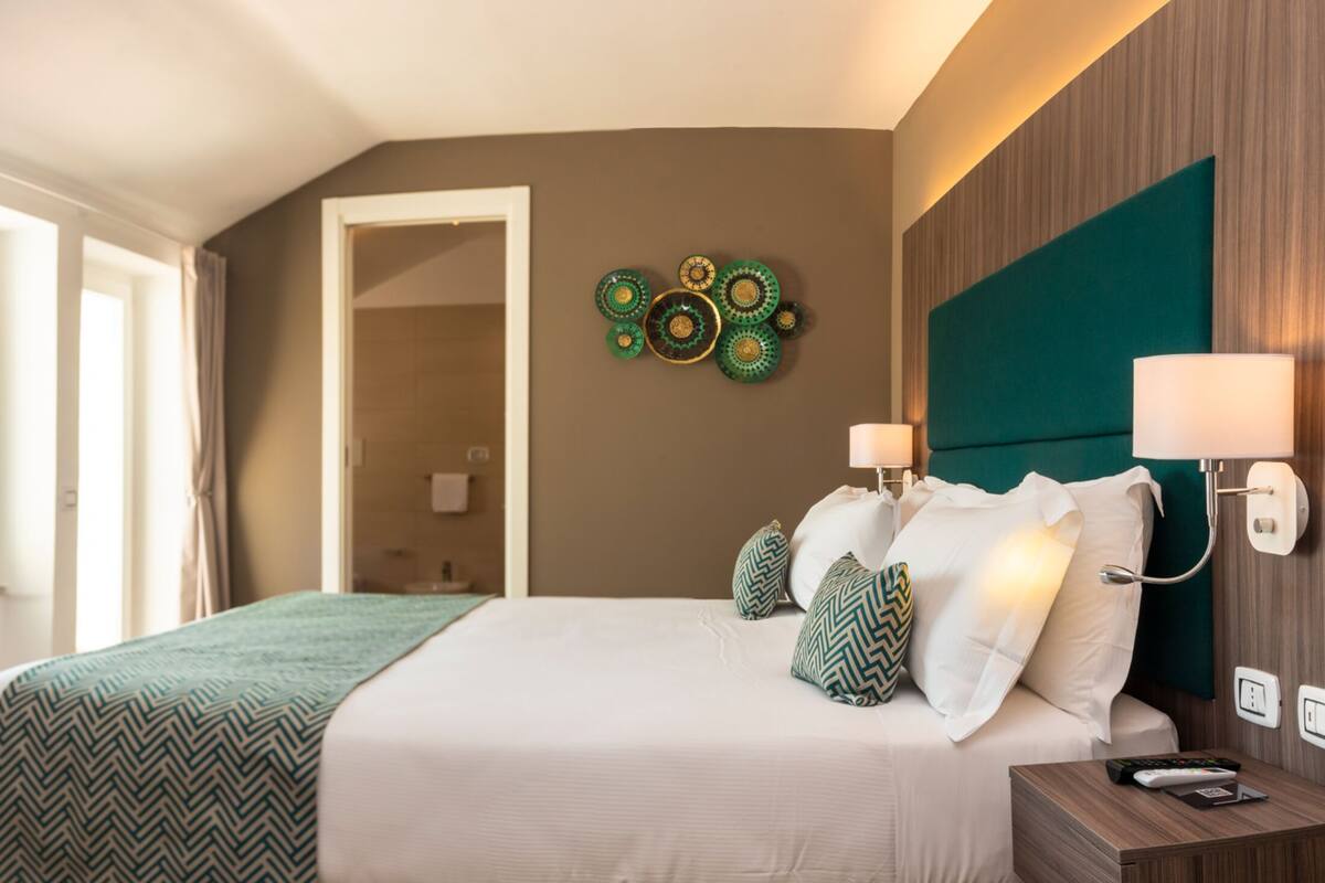Hotelkamer met een bed, een televisie, een wandlamp en een decoratief wandobject.