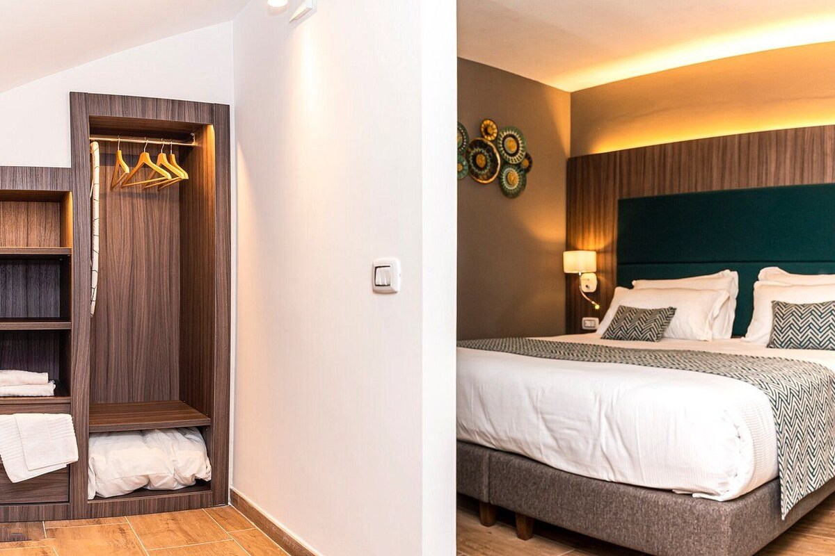 Een hotelkamer met een bed, nachtlampjes, een kledingkast en een decoratief object aan de muur.