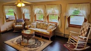 A cozy living room with a sofa, two wicker chairs, a glass coffee table, and a ceiling fan. - Classic Maine House, wrap around deck,  water activity a walk away. (Harpswell)