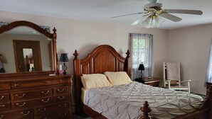 A bedroom with a wooden bed, a dresser, a chair, a ceiling fan, and a window with curtains. - Classic Maine House, wrap around deck,  water activity a walk away. (Harpswell)