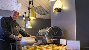 Um chef servindo comida em uma cozinha moderna com sistema de buffet.