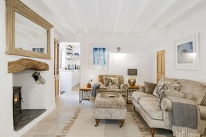 Ein gemütliches Wohnzimmer mit Kamin, einer Couch, einem Couchtisch und einem Essbereich mit Tisch und Stühlen.