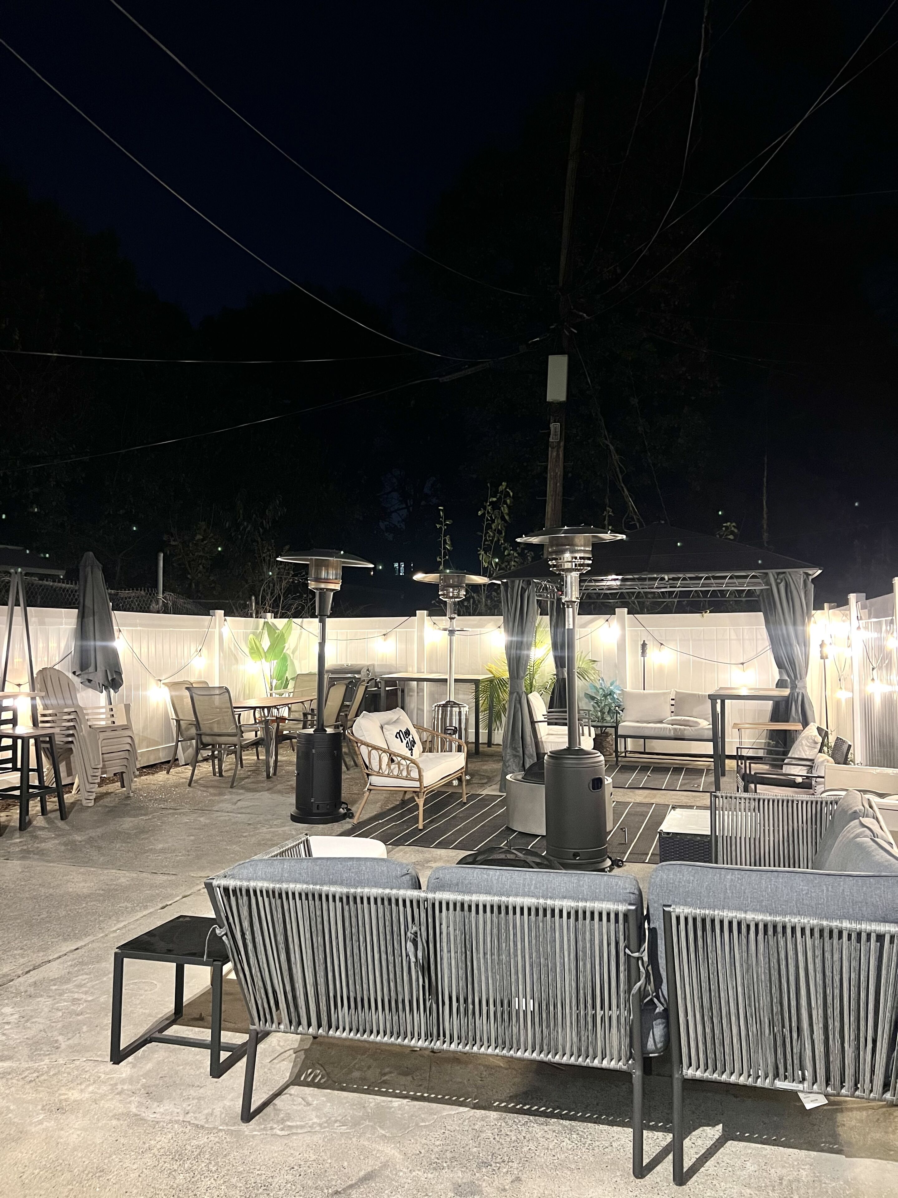 An outdoor patio area with seating arrangements, including chairs and a sofa, and a decorative fire pit.