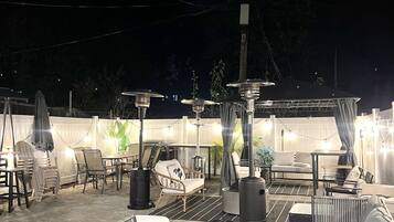 An outdoor patio area with seating arrangements, including chairs and a sofa, and a decorative fire pit.