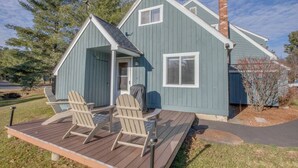 Une maison bleue avec un porche, deux fauteuils Adirondack et une cheminée.