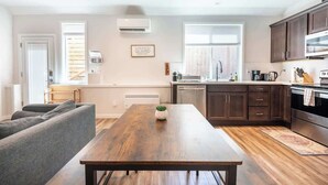 A modern kitchen with dark wooden cabinets, a stainless steel microwave, and a wooden dining table. - Walkable Apt Next to Restaurants, Bars, and Shops! (Portland)