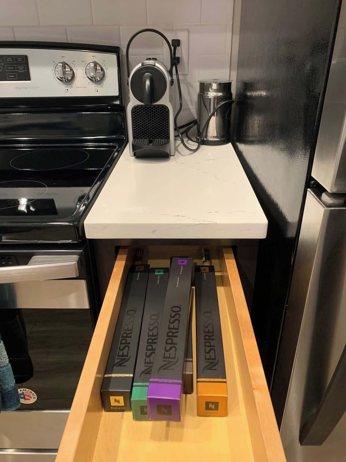 Eine Küche mit Herd, einer Kaffeemaschine und einer Schublade voll Nespresso-Kapseln.