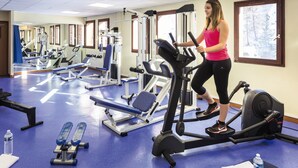 A gym with various exercise equipment, including treadmills and weight machines, and a blue floor. - Belambra Hotel La Plagne « Le Terra Nova » - B&B (La Plagne-Tarentaise)