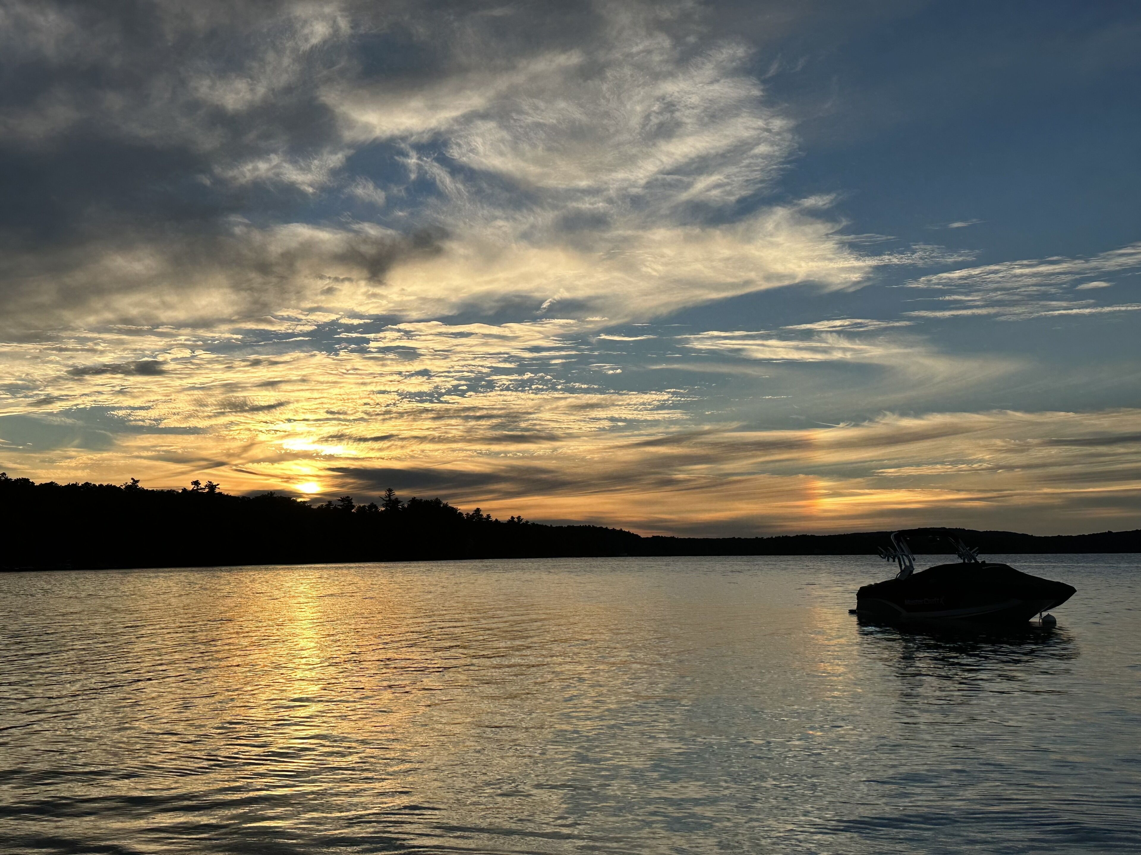 A boat on calm water reflecting the sunset.
