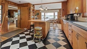 Une cuisine avec des meubles de rangement en bois, un carrelage à carreaux et un coin bar avec des tabourets.