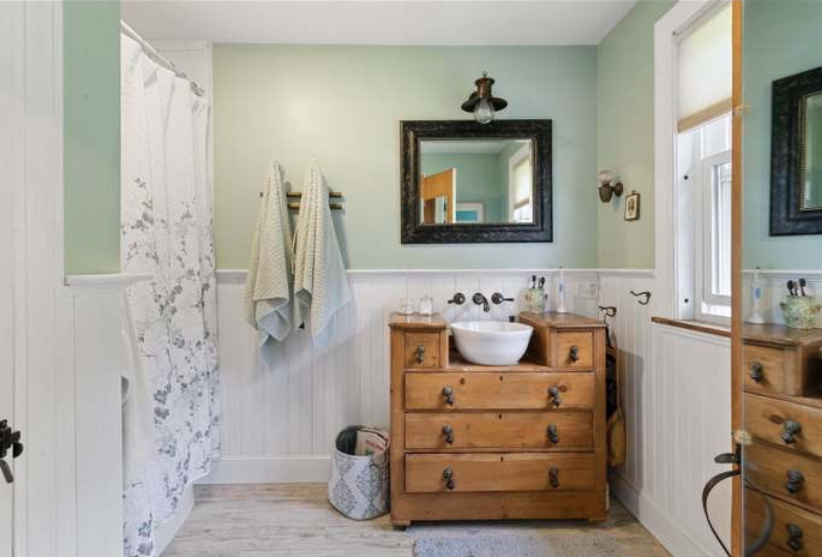 A bathroom with a wooden vanity, a white sink, and a mirror above it.