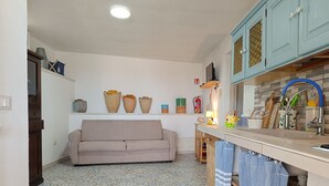 A kitchen with a beige sofa, tiled floor, and light blue cabinets. - Blue House (Castro)
