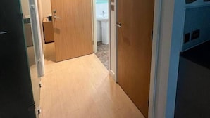 A narrow hallway with wooden doors leading to a bathroom and a kitchenette area. - 1 Bedroom Flat - Lace Market Nottingham (Nottingham)