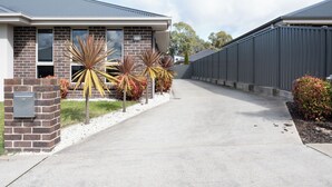 A modern two-story house with a brick facade, large windows, and a concrete driveway. - Cute & Cosy 2 Bedroom Unit with Parking & WiFi (Prospect)