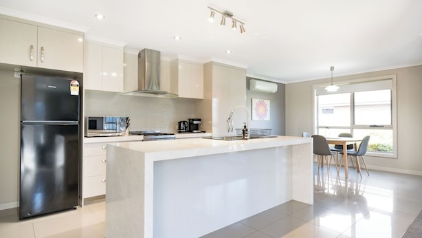 A modern kitchen with a central island, stainless steel appliances, and a dining area with a view. - Cute & Cosy 2 Bedroom Unit with Parking & WiFi (Prospect)