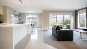 A modern kitchen with a central island, a dining area with a table and chairs, and a living area with a sofa and a coffee table. - Cute & Cosy 2 Bedroom Unit with Parking & WiFi (Prospect)
