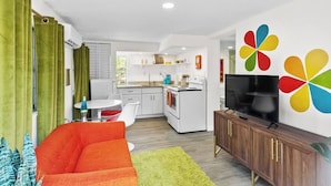 A compact living space with a kitchenette, a dining area, and a TV on a wooden cabinet. - That 70s Themed Apt Close to Coffee, Food and Shops (Tampa)