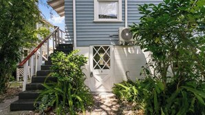 A house with a white door, a staircase, and a small garden with ferns. - That 70s Themed Apt Close to Coffee, Food and Shops (Tampa)