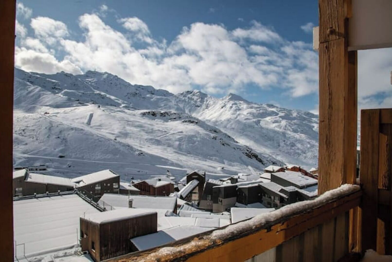 Eine verschneite Berglandschaft mit einem hölzernen Gebäude im Vordergrund.