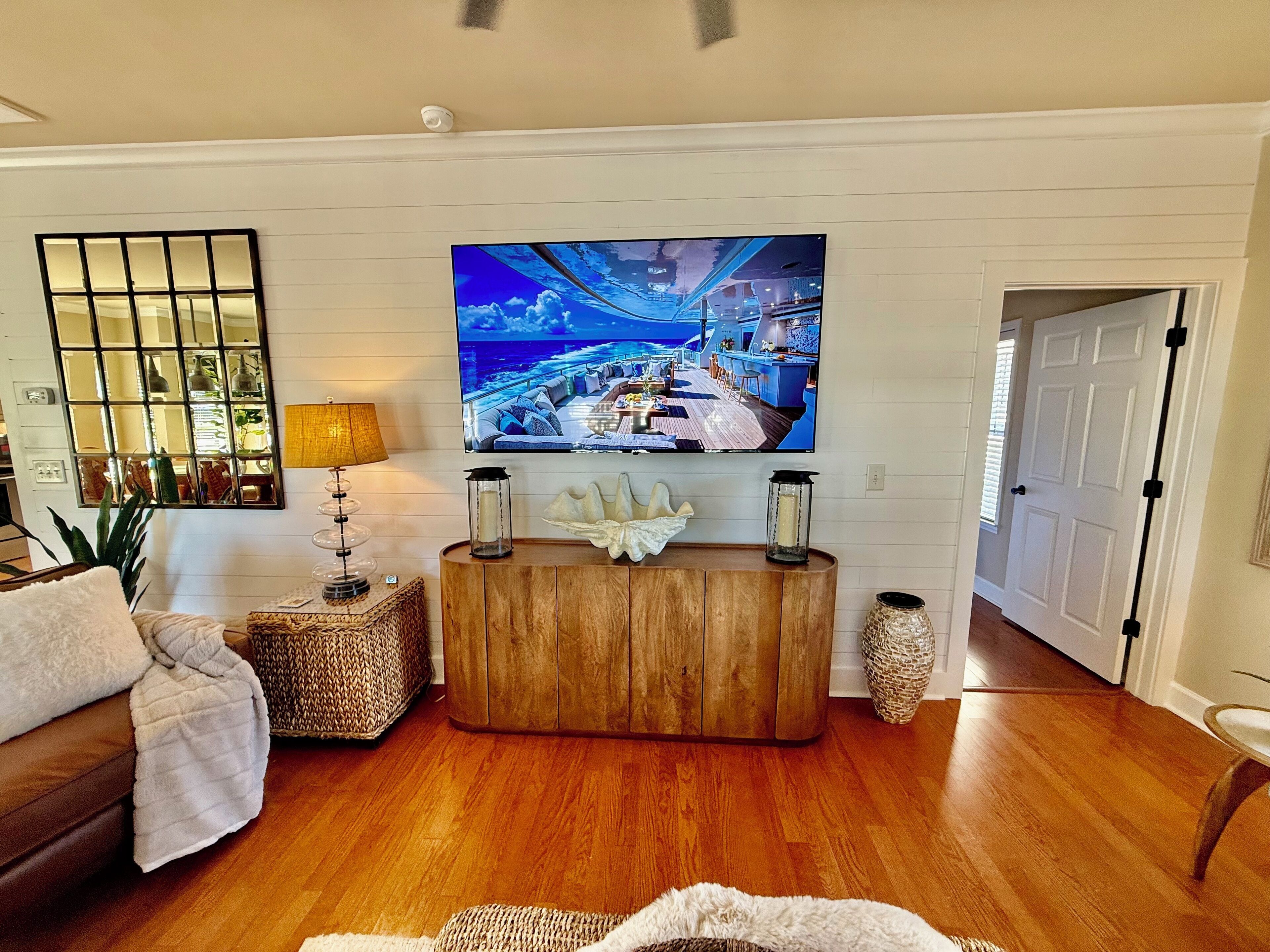A living room with a wooden entertainment center, a large flat-screen TV, a sofa, and a decorative mirror.