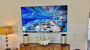 A television displaying a room with a wooden floor, a white console table with decorative items, and a lamp. - Ocean lakes LAKEFRONT MH89A ALL DECKED OUT Newly redecorated (Myrtle Beach)