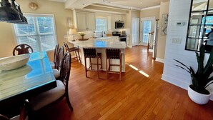 A spacious kitchen with a central island, white cabinetry, and a dining area with wooden chairs. - Ocean lakes LAKEFRONT MH89A ALL DECKED OUT Newly redecorated (Myrtle Beach)