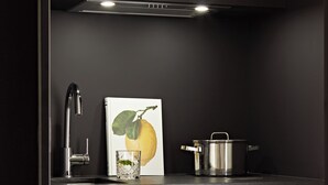 Een moderne keuken met een roestvrijstalen kraan, een glas water, een citroen en een pan op het aanrecht.