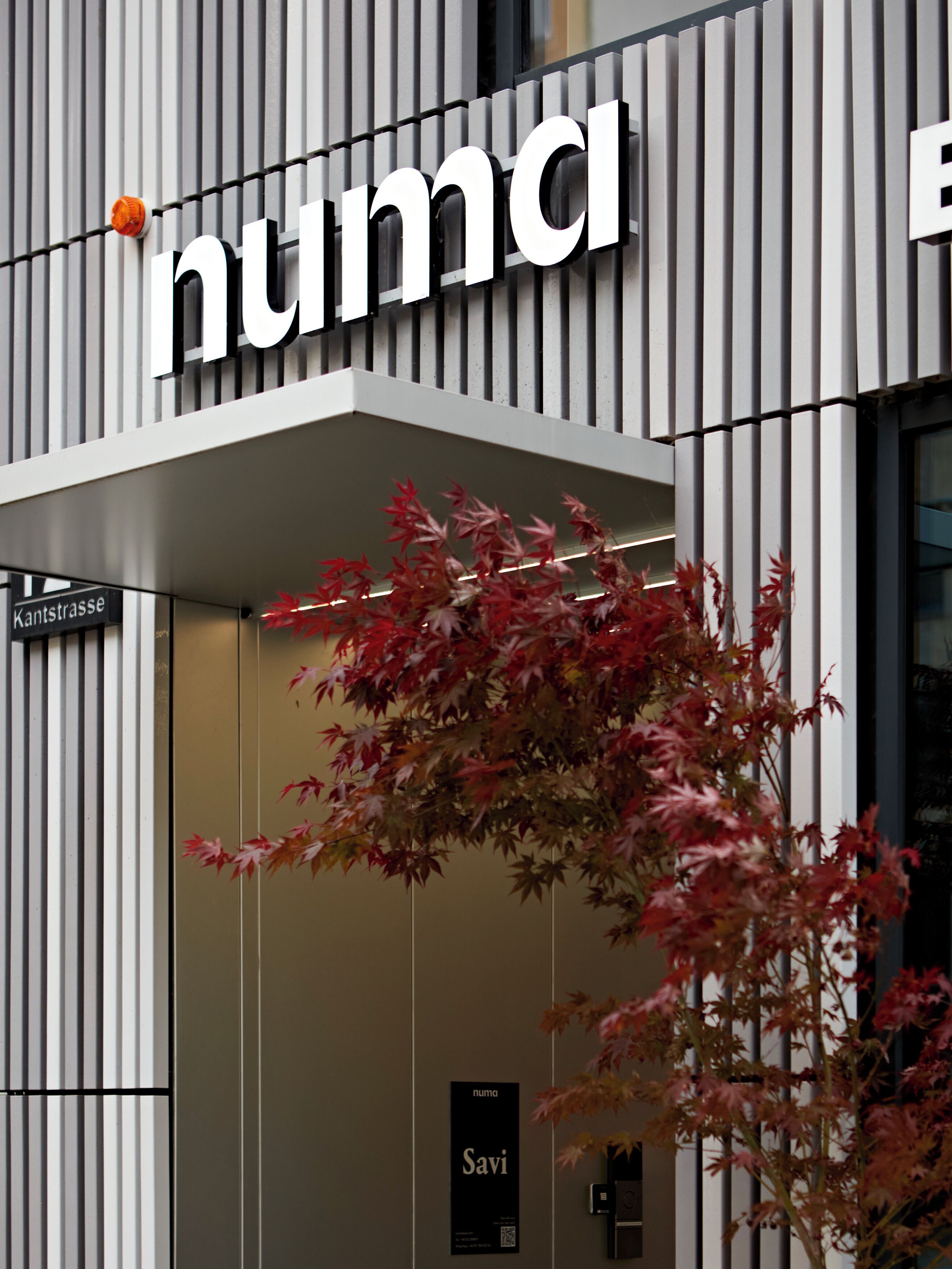 En modern byggnad med en skylt som visar ordet ”numa” och en skylt med ordet ”Savi” på dörren.
