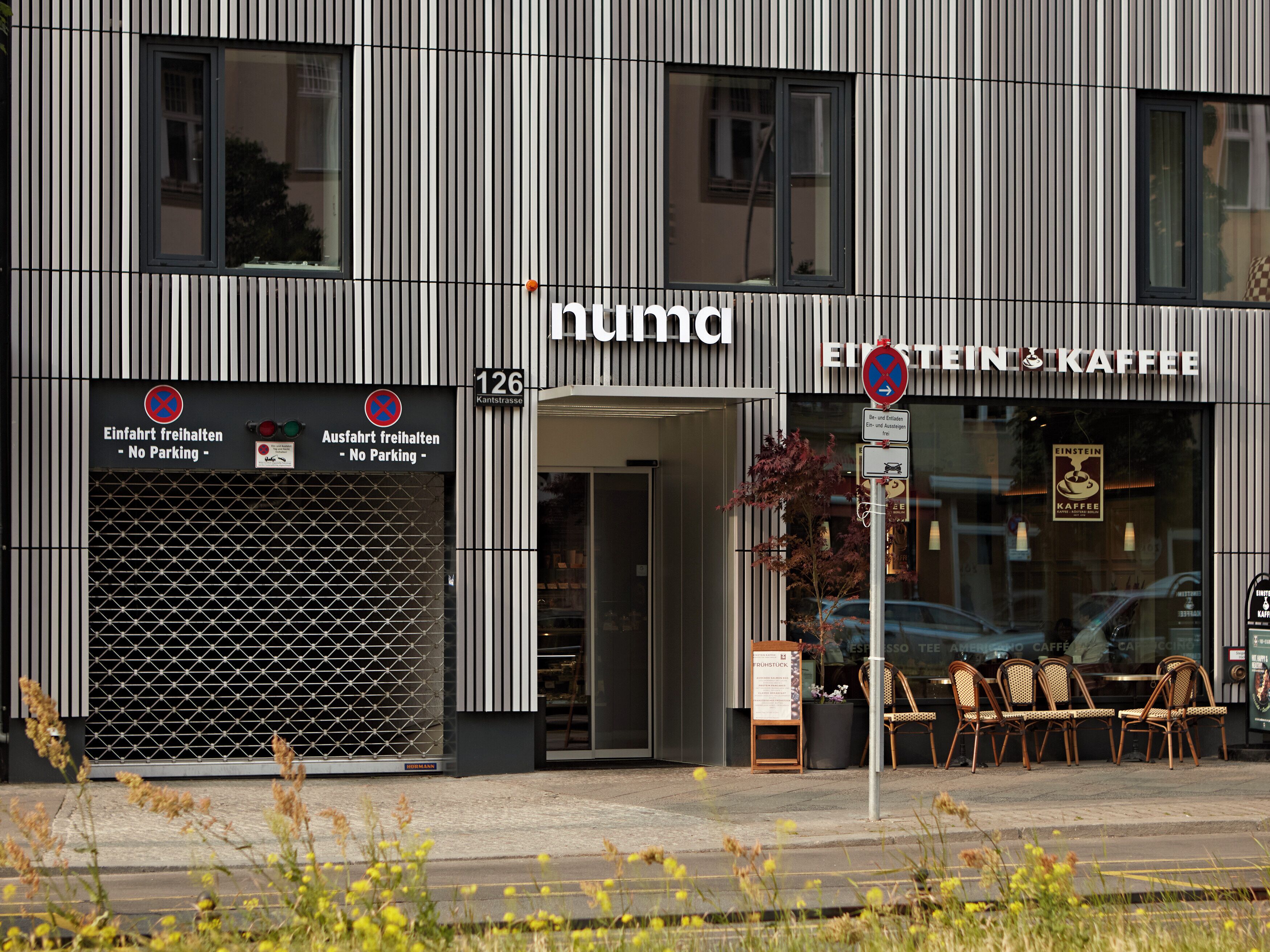 A modern building with a striped facade, a sign indicating no parking, and a storefront for 'Einstein Kaffee'.
