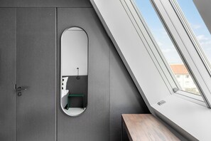 Een moderne badkamer met dakraam, toilet en een groene bank.