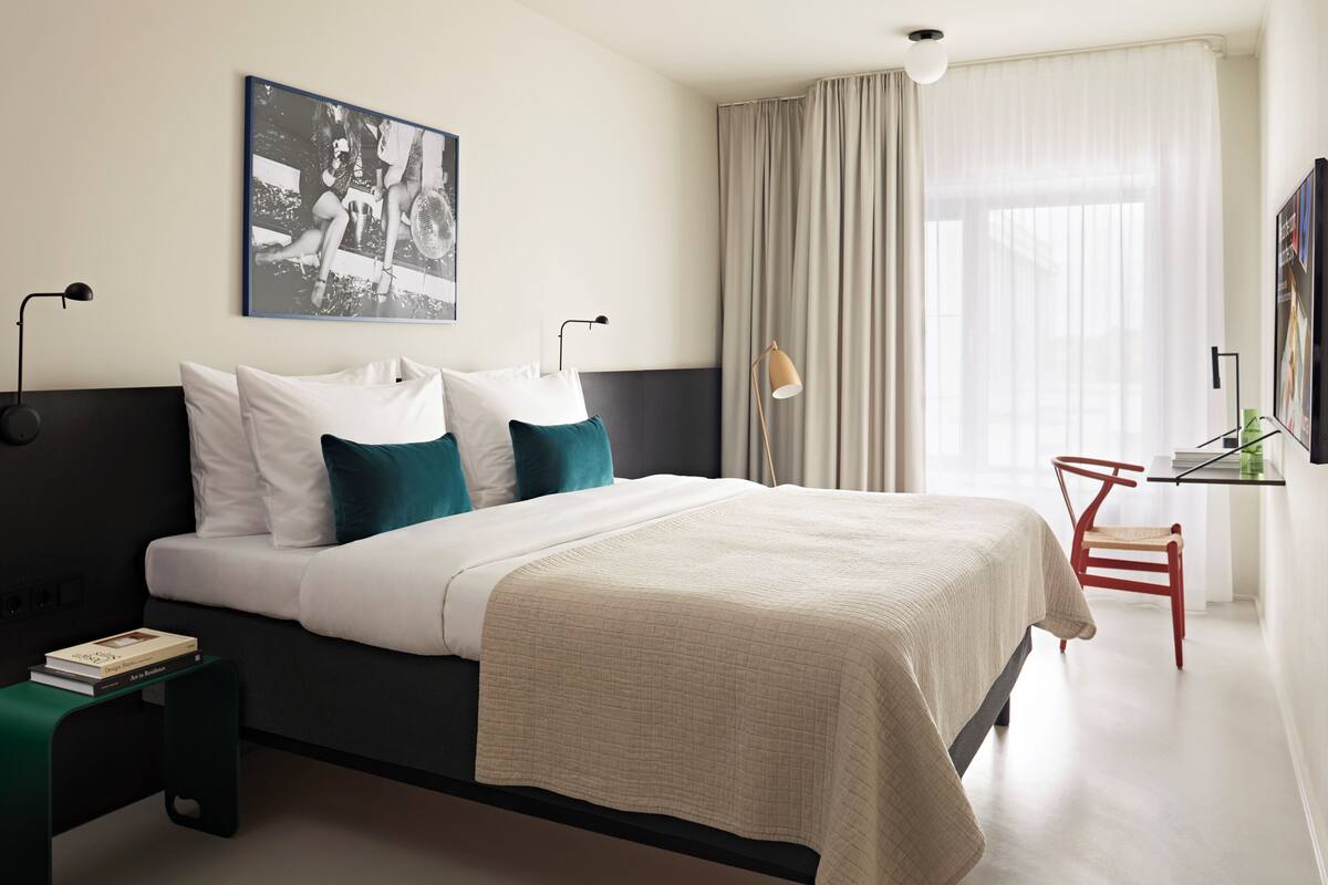 Una habitación de hotel moderna con una cama grande, un escritorio y una silla.