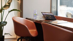 Een moderne kantoorruimte met een laptop op een marmeren tafel, een potplant en een stoel.