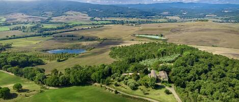 Vista aérea de un paisaje rural con colinas ondulantes, un lago pequeño y árboles dispersos.